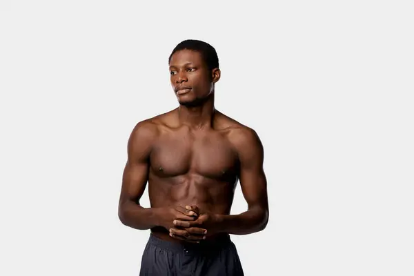 A shirtless African American man stands confidently against a white background in a studio setting. — Stock Photo