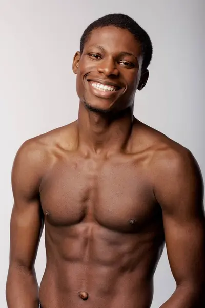 Un Afro-Américain pose en toute confiance dans un studio, présentant sa routine beauté sans chemise. — Photo de stock