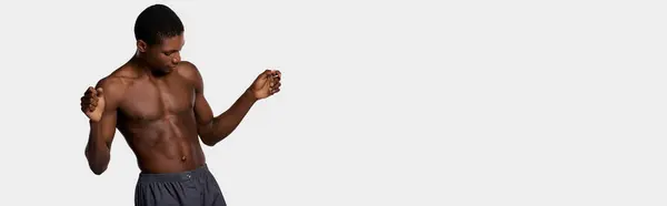An African American man stands shirtless against a pure white backdrop, showcasing a beauty routine. — Stock Photo