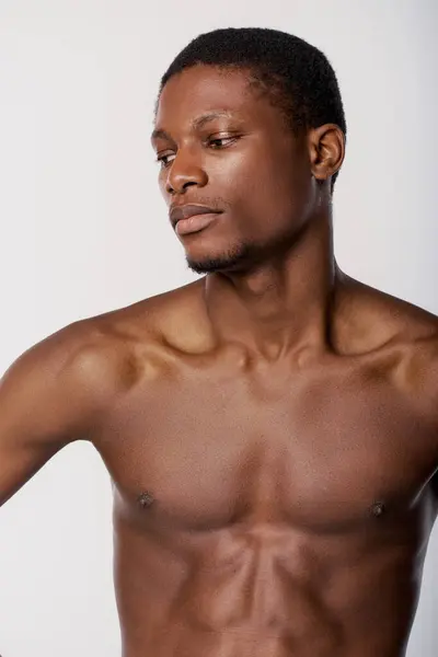 A confident shirtless African American man poses in a studio with a white background for a beauty routine. — Stock Photo