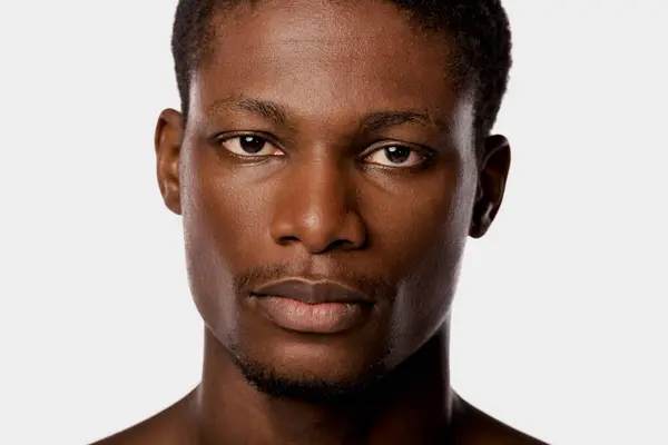 Close-up shot of an African American man showcasing his beauty routine in a studio with a white backdrop. — Stock Photo