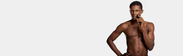 Shirtless African American man exhibiting self-confidence and strength against a white backdrop. — Stock Photo