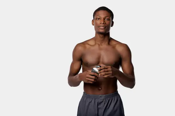 Shirtless African American man holding a can of beer, showcasing his bold beauty routine in a studio with a white background. — Stock Photo