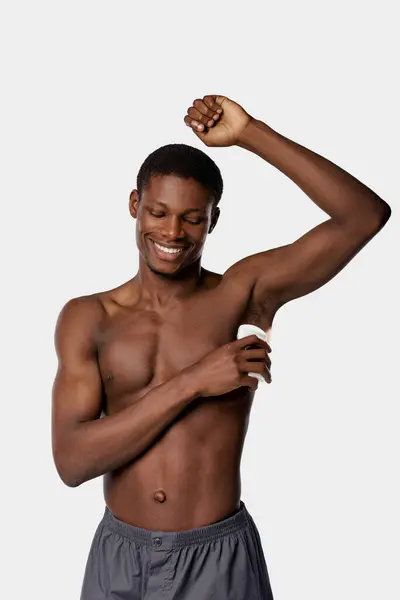 Shirtless African American man flexing his muscles with a towel in a studio against a white background. — Stock Photo