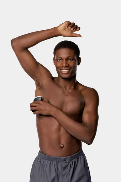 An African American man, shirtless, proudly holding a can of beer against a clean white backdrop. — Stock Photo