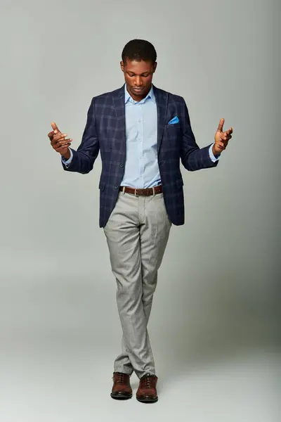 Afroamerikanischer Geschäftsmann im karierten Blazer, steht mit erhobenen Händen in der Luft. — Stockfoto