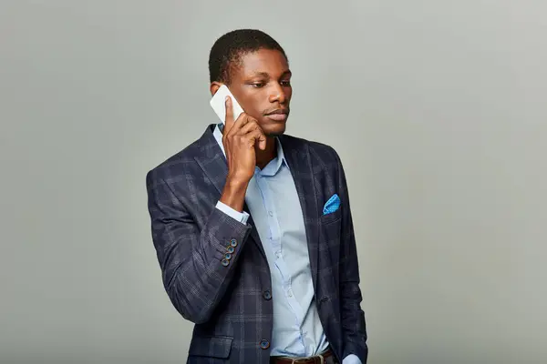 Hombre de negocios afroamericano en una chaqueta a cuadros hablando en un teléfono celular, exudando profesionalismo y enfoque. - foto de stock
