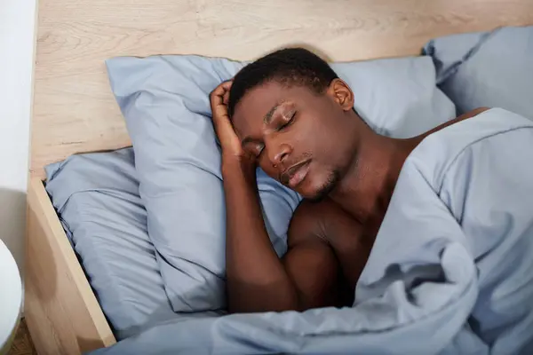 Schöner Mann entspannt sich auf dem Bett, den Kopf auf der Hand gestützt. — Stockfoto