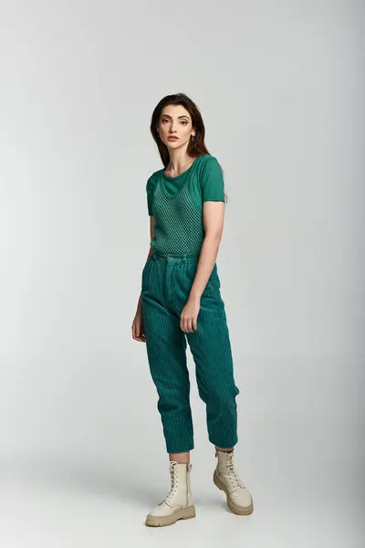 A young woman in a green corduroy outfit stands against a white backdrop. — Stock Photo