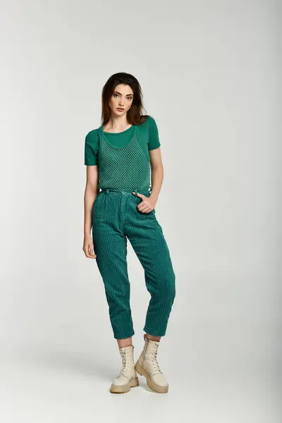 A young woman in green corduroy pants and a matching top poses against a white background. — Stock Photo