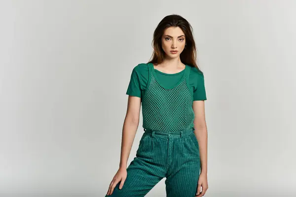 A young woman in a green outfit stands confidently against a white background. — Stock Photo