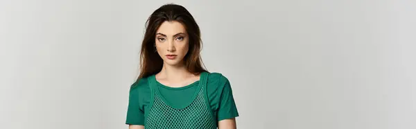 A young woman with long brown hair wears a green mesh top and looks directly at the camera. — Stock Photo