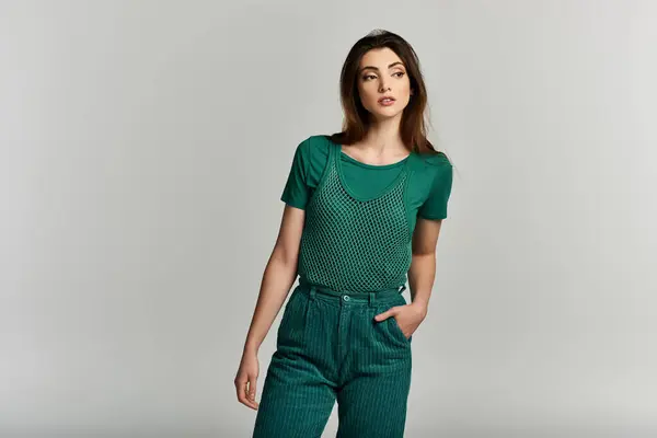 A young woman wearing a green outfit stands against a white background. — Stock Photo