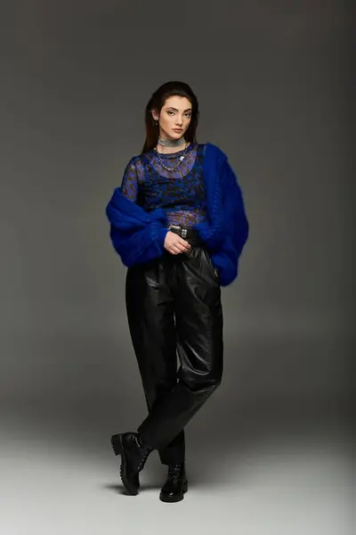 A young woman in a blue fuzzy jacket and black leather pants poses for a photoshoot. — Stock Photo