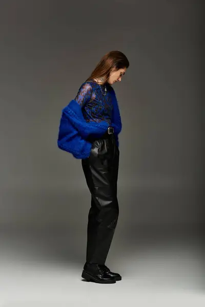 Una joven vestida con un atuendo elegante con una chaqueta azul se encuentra en un entorno de estudio. - foto de stock