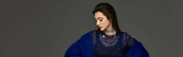 A young woman in a blue outfit, looking downwards in a moment of thought. — Stock Photo
