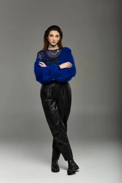 A young woman poses in a stylish blue cardigan and black leather pants. — Stock Photo