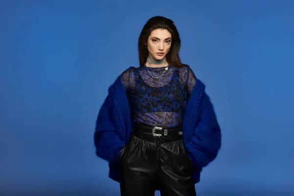 Une jeune femme en manteau de fourrure bleu pose sur un fond bleu vif. — Photo de stock