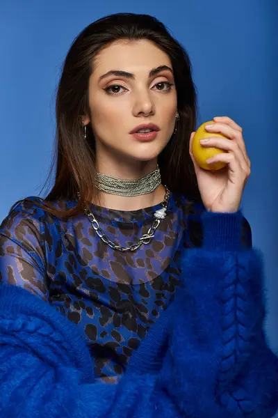 A young woman in a blue fuzzy sweater holds a lemon. — Stock Photo