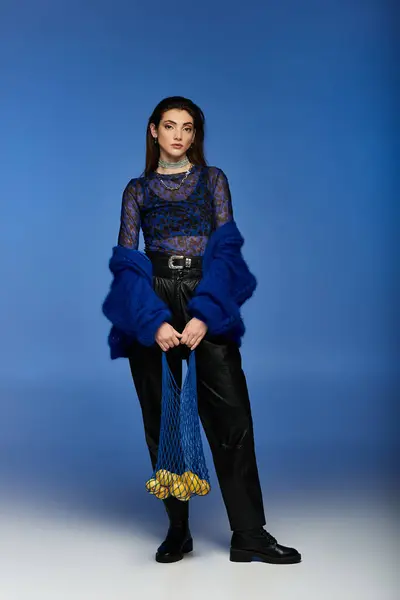 Young woman with mesh bag of fruits on blue backdrop. — Stock Photo