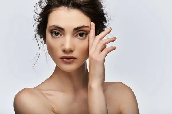 Elegant young woman gazing at camera while caressing cheek. — Stock Photo