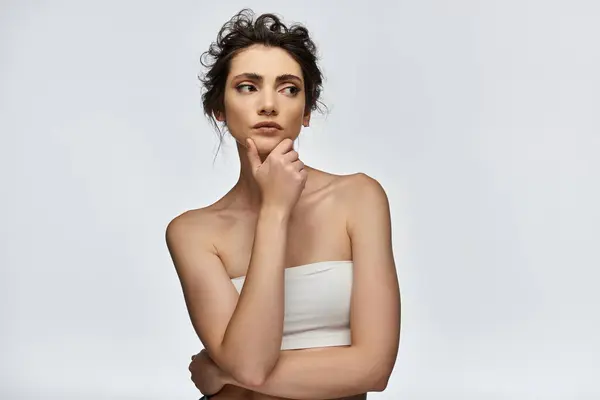 A young woman in a white strapless top stares thoughtfully into the distance. — Stock Photo