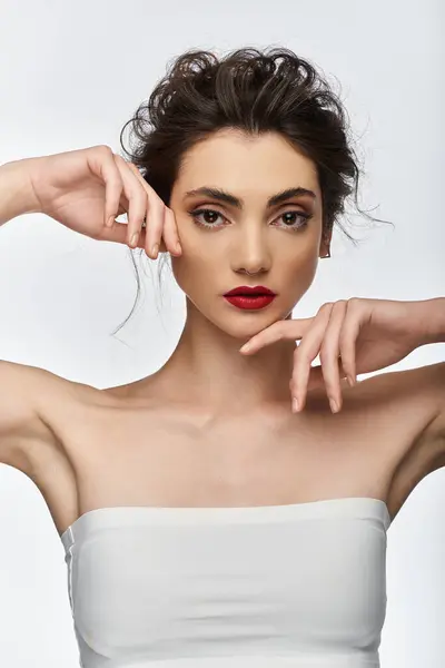 A young woman in elegant attire poses with her hands near her face. — Stock Photo