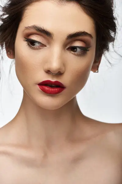 A young woman with dark hair and red lipstick gazes downward. — Stock Photo