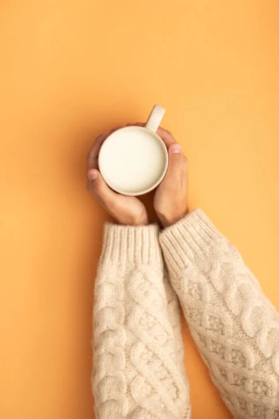 hands grabbing milk mug woolen sweater
