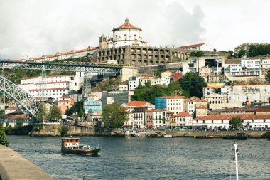 Porto, Portekiz 'in çarpıcı manzarası, ikonik Dom Lus I Bridge, renkli tepe binaları ve Serra do Pilar Manastırı. Douro Nehri ön planda geleneksel bir tekneyle akıyor..