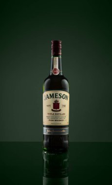 Klasik bir şişe Jameson İrlanda viskisi. Koyu yeşil arka planda sergileniyor. Görüntü, şişenin zarif tasarımını ve zengin markalaşmasını vurguluyor. Pazarlama ve reklam amaçlı mükemmel..