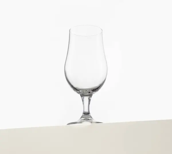 stock image A clear, empty wine glass is elegantly displayed against a plain white background. The glassware's sleek and simple design emphasizes its clean lines and transparency