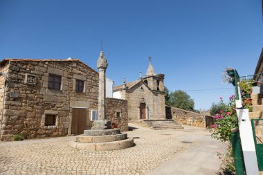 charming church square of Idanha-a-Velha, a historic village in Portugal. Featuring medieval stone buildings, a rustic church, and a cobblestone street, the scene reflects the rich cultural and architectural heritage clipart