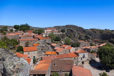  Portekiz 'in tarihi Sortelha köyünün pitoresk bir manzarası. Parlak mavi gökyüzünün altında taş evler ve antik kale duvarları bulunuyor. Bu büyüleyici ortaçağ köyü Portekiz kültür mirasının mükemmel bir örneğidir..