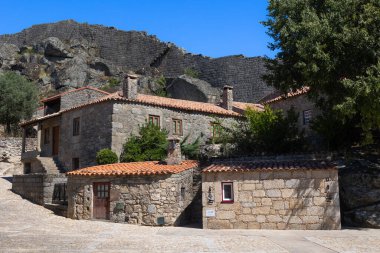 Portekiz 'in tarihi Sortelha köyünün pitoresk bir manzarası. Parlak mavi gökyüzünün altında taş evler ve antik kale duvarları bulunuyor. Bu büyüleyici ortaçağ köyü Portekiz kültür mirasının mükemmel bir örneğidir..