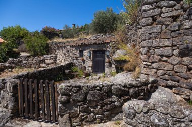  Portekiz 'in tarihi Sortelha köyünün pitoresk bir manzarası. Parlak mavi gökyüzünün altında taş evler ve antik kale duvarları bulunuyor. Bu büyüleyici ortaçağ köyü Portekiz kültür mirasının mükemmel bir örneğidir..