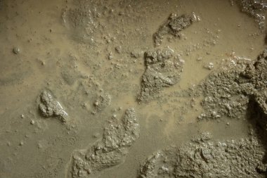 Yakın çekim, taze karışık çimentonun pürüzlü, ıslak dokusunu yakalıyor. Görüntü, yapıda kullanılan malzemelerin ham ve tamamlanmamış doğasını vurgulayarak taneciklerin detaylarını ve düzensiz yüzeyini vurguluyor..