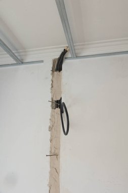 Görüntü, açıkta duran kablolar ve sahte tavan kurulumu ile tamamlanmamış bir ev yenileme projesini gösteriyor. Duvar elektrik kabloları için açık ve tavan iskeleti kısmen kurulmuş..