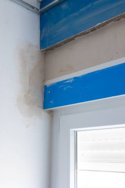 Pencere çerçevesini yeni yenilenmiş bir duvara sığdırmak için taze çimento ve tuğla işçiliğini gösteren bir PVC pencere kurulum sürecinin yakın çekimi. Resim pencere yerleşiminin hassasiyetini vurgular