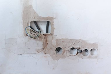 Elektrik kablolarının ve bağlantı kutularının olduğu kısmen bitmiş bir duvar resmi. Konut yenileme, elektrik tesisatı ve inşaatla ilgili iş ve süreçlerin teşhir edilmesi için ideal.