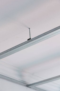 Görünür metal iskeleti olan askıya alınmış bir tavan kurulumunun yakınlaştırılması, sahte tavan yapısının teknik detaylarını gözler önüne seriyor. İnşaat, yenileme ve iç tasarım projeleri için ideal.
