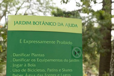 Lizbon 'daki Jardim Botnico da Ajuda' da bahçeyi koruma kurallarını gösteren yeşil bir tabela. Bereketli yeşilliklerle çevrelenmiş olan yasada, çevre bilinci ve park yönetmelikleri vurgulanıyor.