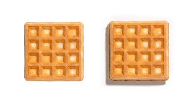 Beyaz arka planda yan yana yerleştirilmiş iki altın kare waffle 'ın üst görüntüsü. Gevrek bir dokuya ve açık renge sahip mükemmel pişirilmiş, kahvaltı ya da atıştırmalık fotoğrafçılık için ideal..
