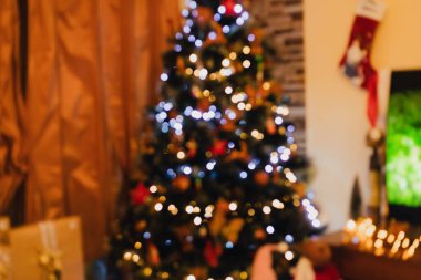 Parlak ışıklar ve süslemelerle süslenmiş güzel dekore edilmiş bir Noel ağacıyla sıcacık bir ev. Yumuşak bokeh etkisi, tatil sezonunun sıcaklığını ve şenlik havasını vurguluyor..