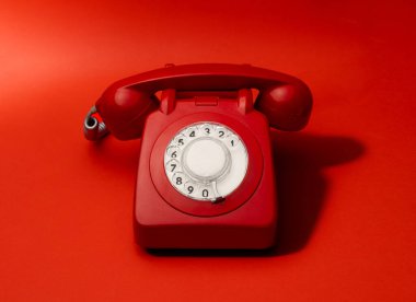 A vibrant red vintage rotary telephone on a matching red background. The bold monochromatic theme highlights its classic design, evoking nostalgia and showcasing timeless simplicity. clipart