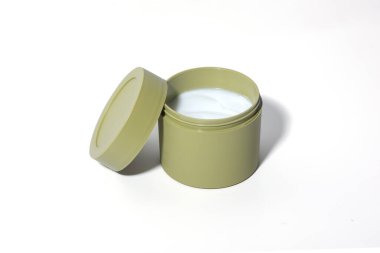 Açık zeytin yeşili kozmetik kavanozunun beyaz kremayla doldurulduğu minimalist bir güzellik ürünü. Temiz beyaz bir arkaplanda yakalanan bu yüksek kaliteli görüntü cilt bakımı ve güzellik damgası için mükemmeldir..