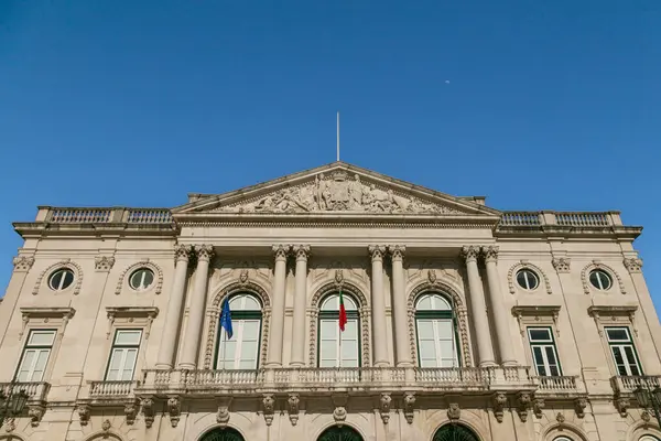 Lizbon Belediyesi 'nin (Cmara Belediyesi de Lisboa) klasik mimari, Portekiz ve AB bayraklarıyla berrak mavi bir gökyüzü altında ön manzarası. Lizbon 'un kalbinde tarihi bir dönüm noktası.
