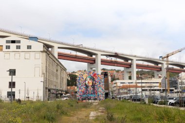 Lisbons LX Fabrikası 'nda ele geçirilen bu fotoğraf, otoyol köprülerinin altında renkli bir duvar resmi gösteriyor. Canlı, endüstriyel ve kültürel bir şehirde kentsel sanat ve mimariyi harmanlıyor..