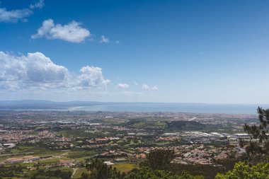 Portekiz, Sintra 'daki Santa Eufmia' dan panoramik manzara açık güneşli bir günde mavi gökyüzü, kentsel bölgeler ve Atlantik Okyanusu ile geniş kıyı manzarasını yakalıyor..