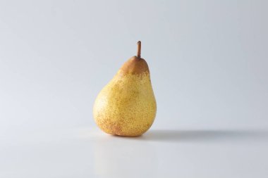Olgun sarı bir armut, yumuşak doğal ışıkla yakalanan temiz beyaz bir zemin karşısında tek başına duruyor. Bu minimalist stüdyo çekimi onun dokusunu ve şeklini zarif bir sadelikle ön plana çıkarıyor.
